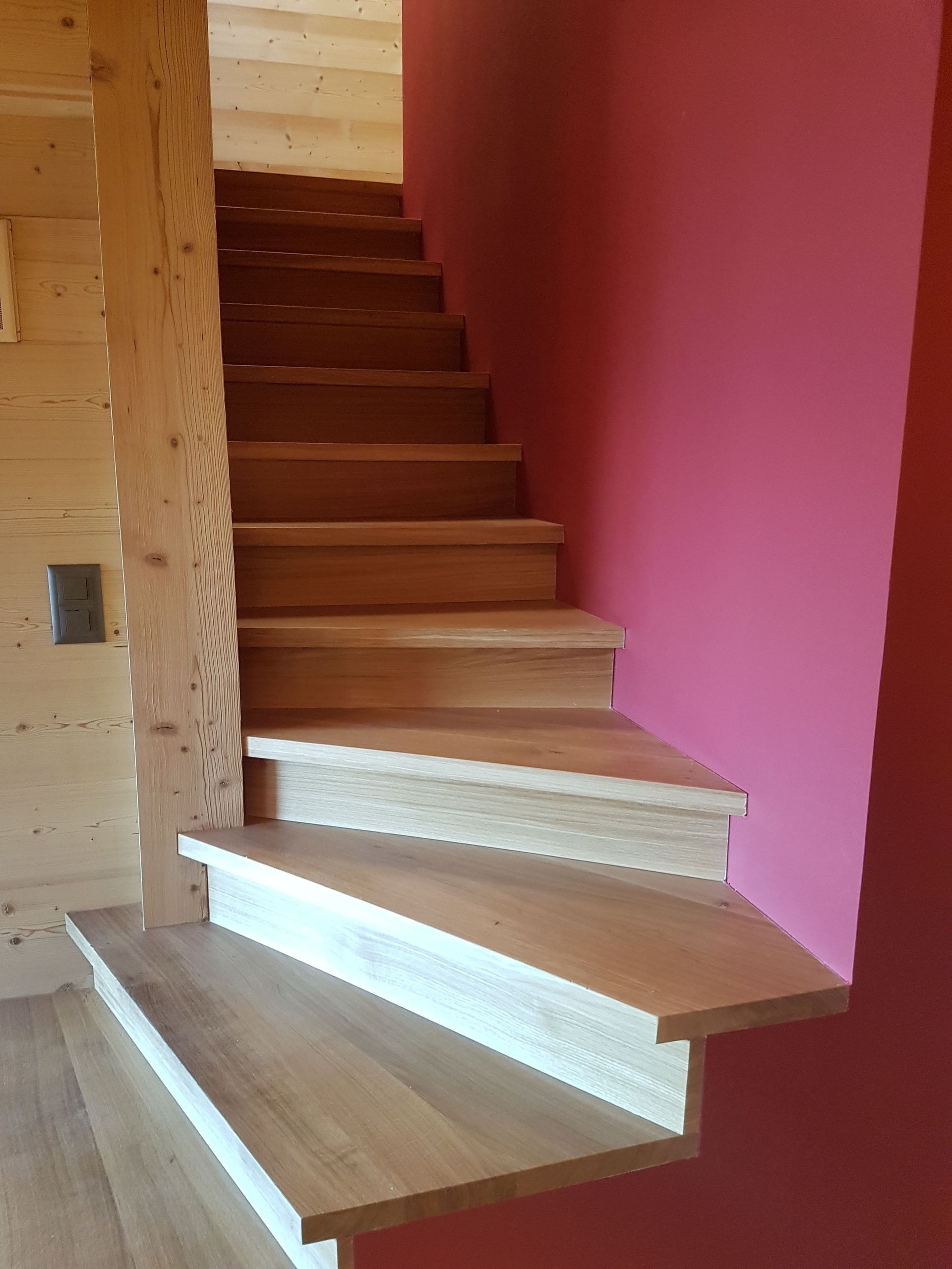 Escalier en bois avec murs roses et moulures blanches à l'intérieur d'une maison