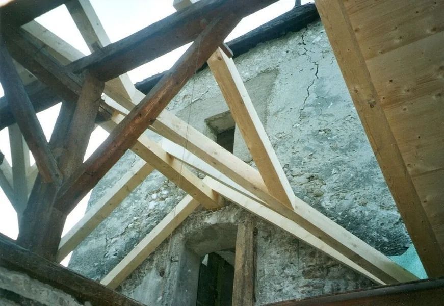 Charpente de toit en bois en construction à l'intérieur d'une structure brute en pierre ou en béton.