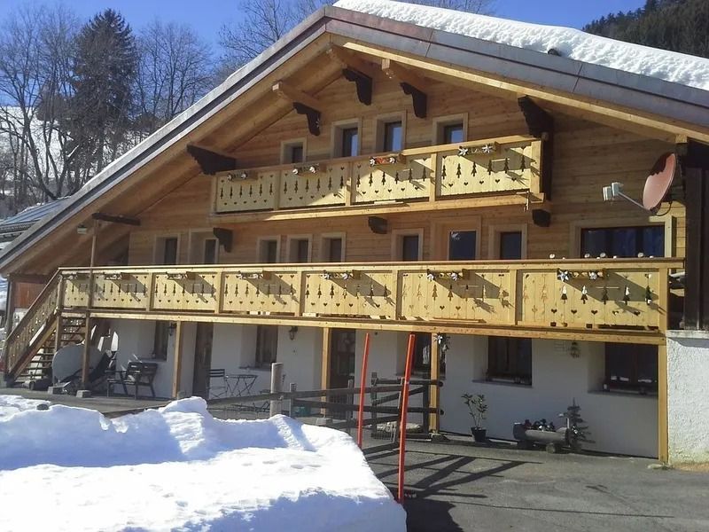Chalet en bois aux balcons enneigés par une journée d'hiver ensoleillée