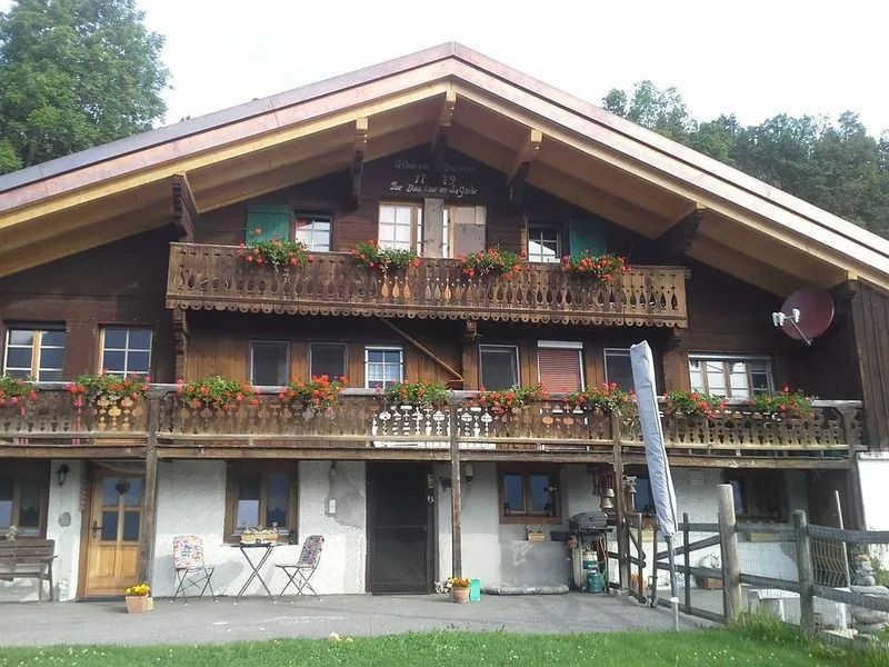 Chalet alpin en bois avec balcons fleuris et patio rustique devant