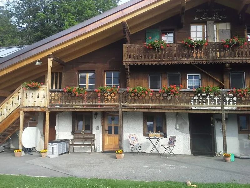 Maison de style chalet avec balcons en bois, jardinières et chaises d'extérieur sous un toit en pente
