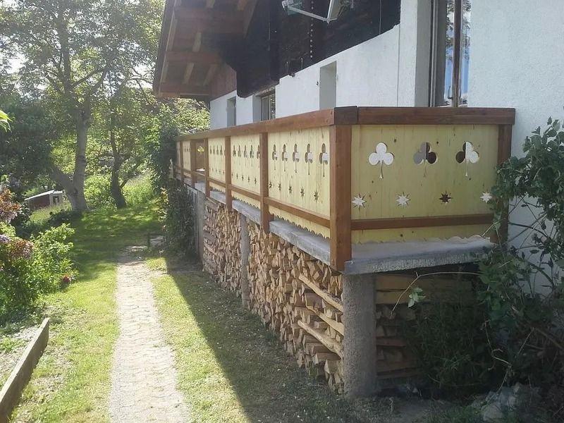 Porche en bois avec rambarde jaune donnant sur un chemin herbeux et des arbres à l'extérieur