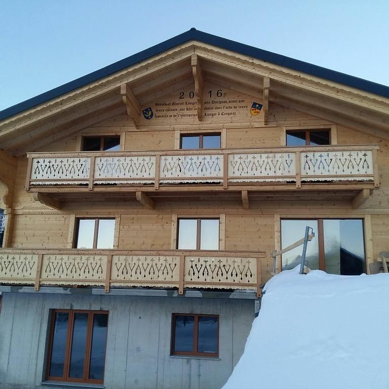 Chalet en bois avec balcons sculptés et toit enneigé sous un ciel bleu clair