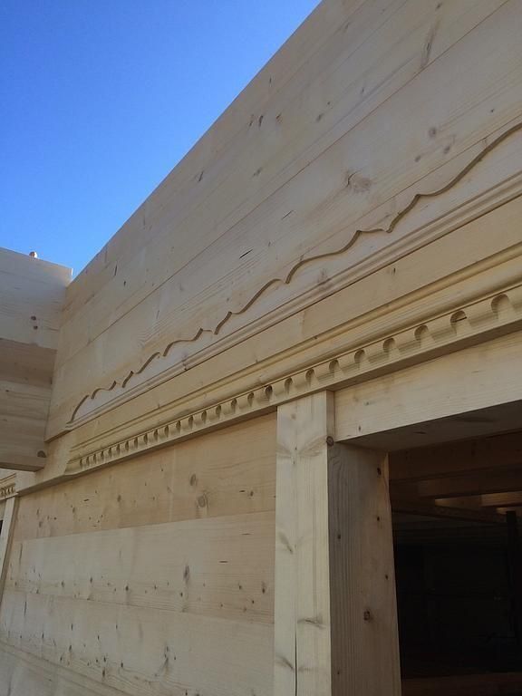 Gros plan sur la façade en bois d'un bâtiment orné de moulures décoratives sous un ciel bleu