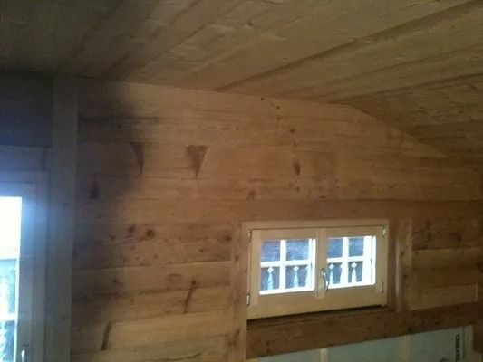 Pièce lambrissée avec une petite fenêtre et un plafond en bois incliné