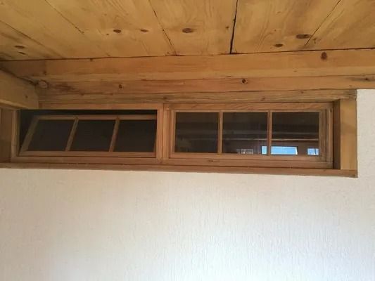 Mur en bois avec deux petites fenêtres au-dessus d'un mur intérieur blanc