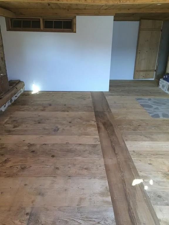 Pièce vide non aménagée avec parquet, lambris blancs et rangements intégrés le long du mur du fond