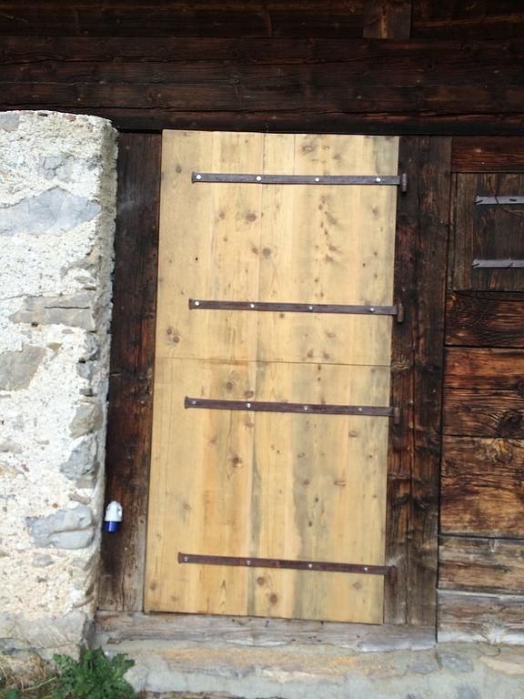 Porte en bois avec des bandes de métal sombre encastrées dans un mur rustique en pierre et en bois