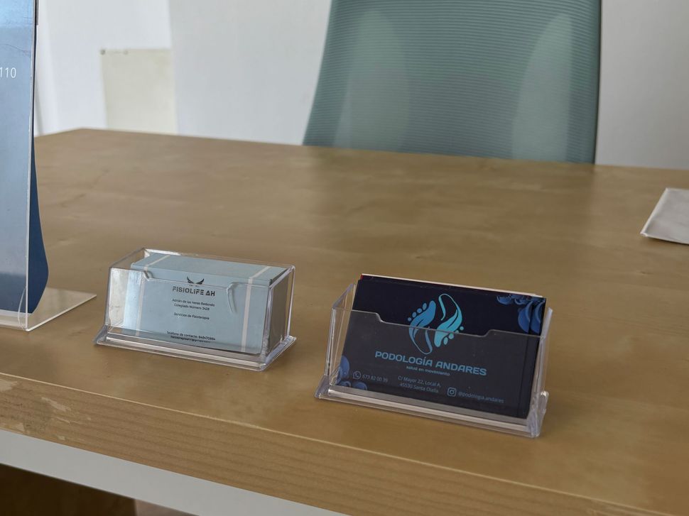 Dos placas de identificación de acrílico sobre una mesa de madera en una sala de conferencias.