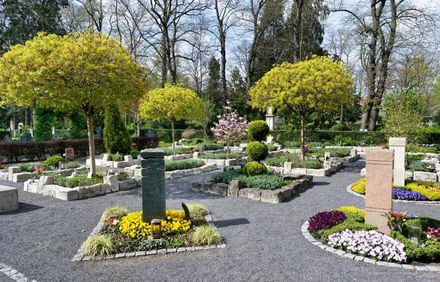 Formaler Garten mit farbenfrohen Blumenbeeten, Kieswegen und im Frühling geschnittenen Bäumen