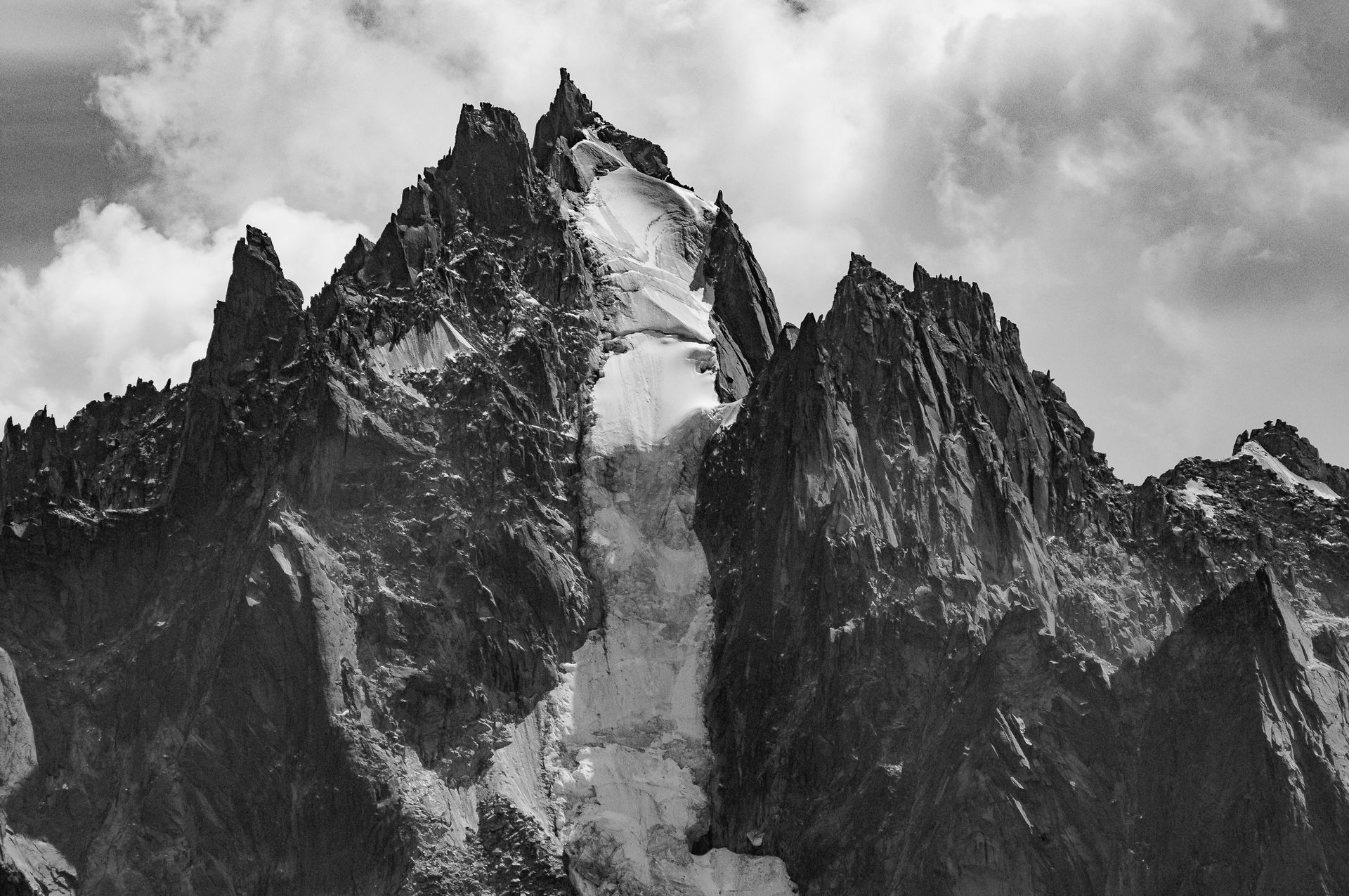 Picos de montañas irregulares con nieve y nubes.