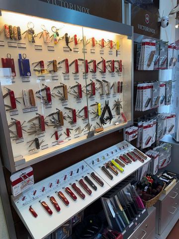 Eine Vitrine gefüllt mit roten, silbernen und schwarzen Schweizer Taschenmessern, die zum Verkauf angeboten werden.