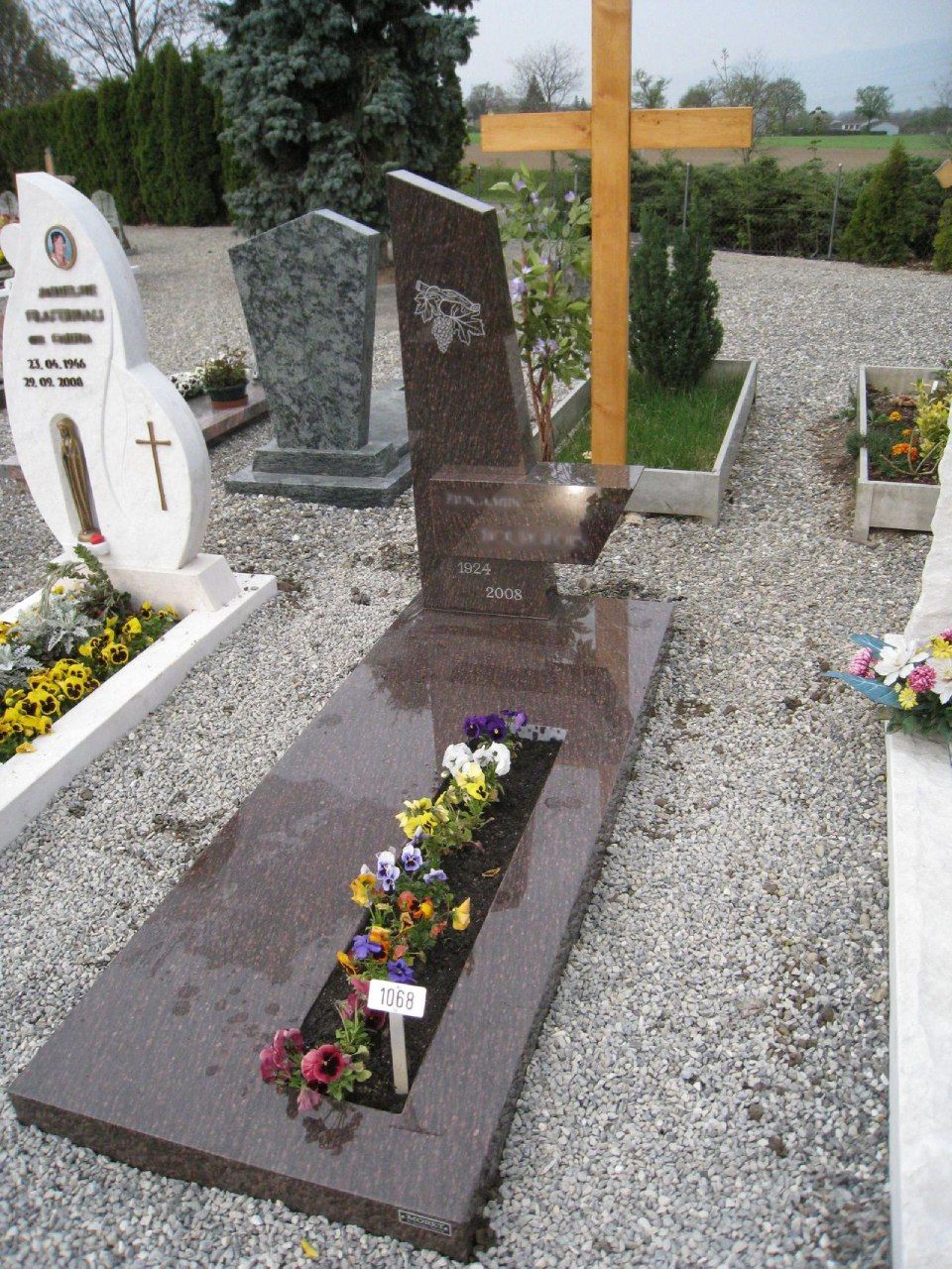 Une tombe dans un cimetière avec des fleurs et une croix