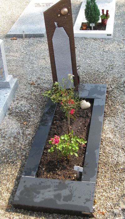 Une tombe avec des fleurs et des rochers dedans