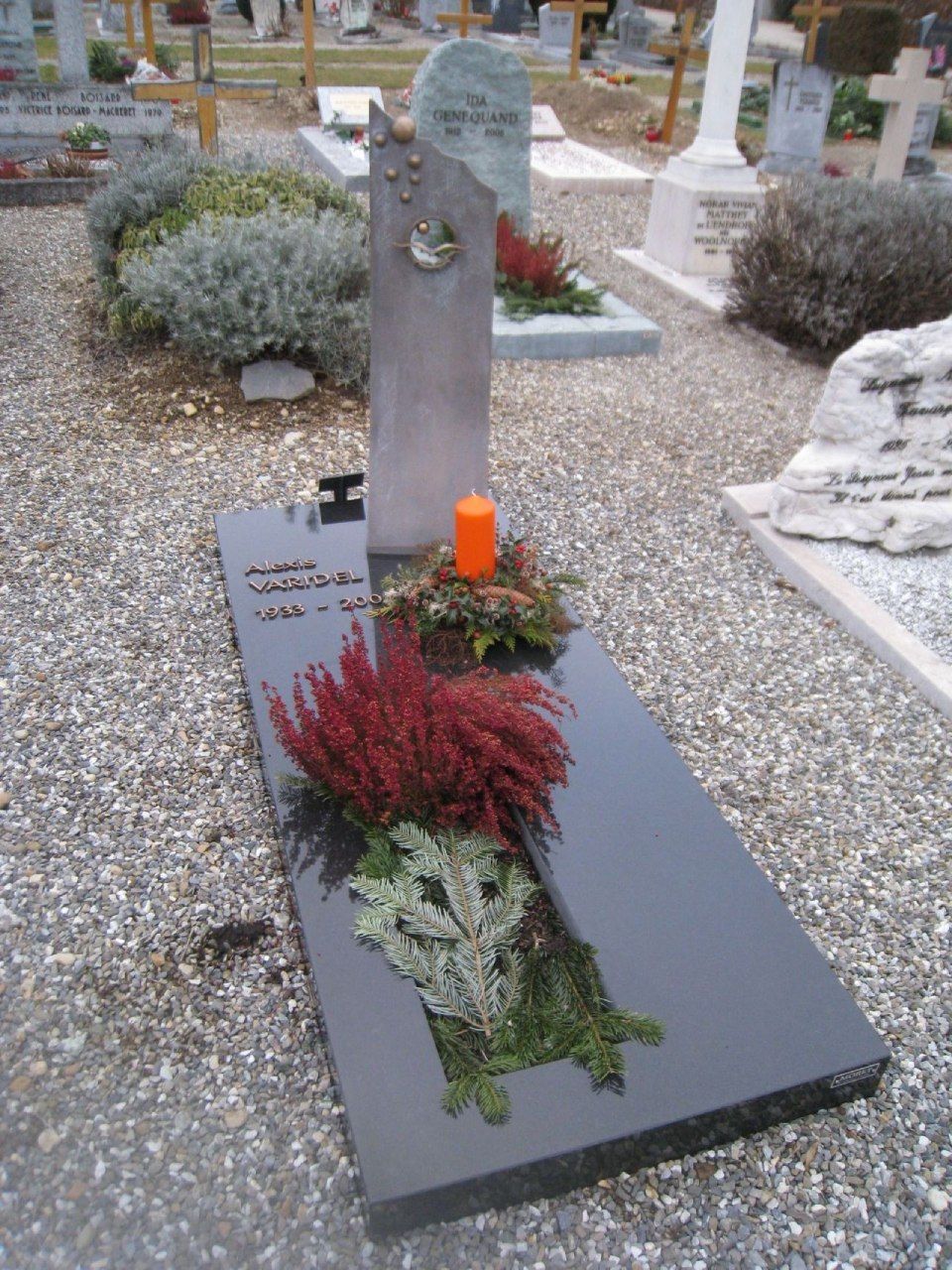 Une tombe dans un cimetière avec des fleurs et une bougie