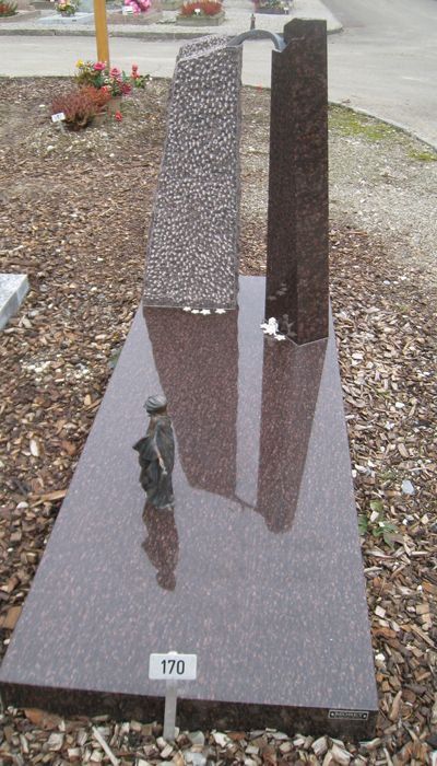 Une tombe surmontée d'une statue dans un cimetière.