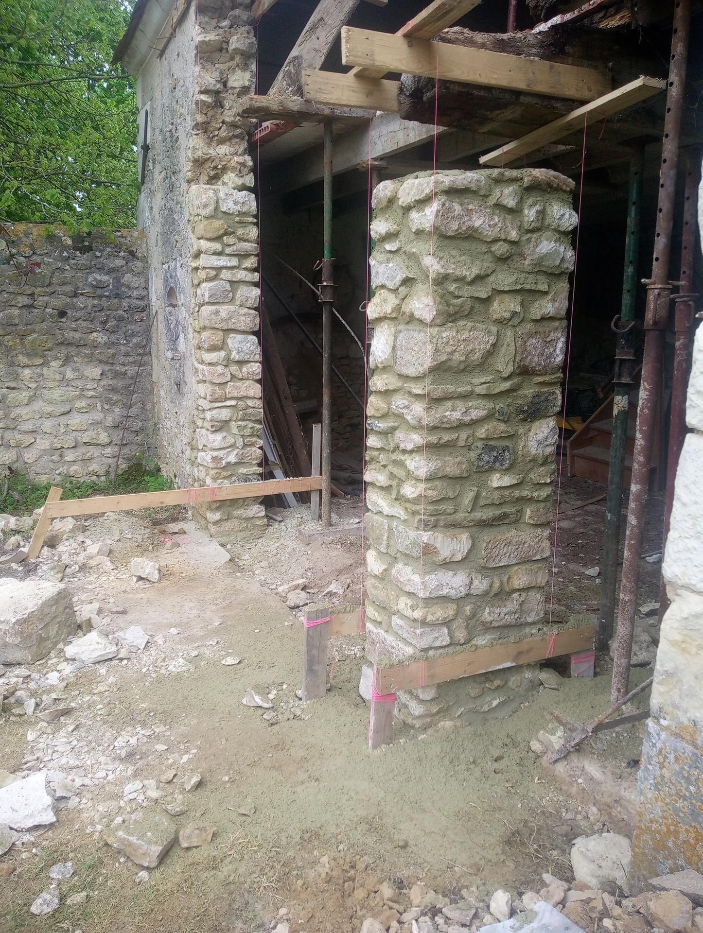 Bâtiment en pierre en construction avec des supports en bois.