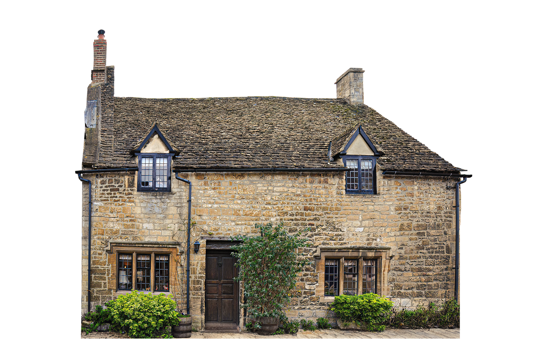 Maisonnette en pierre avec toit d'ardoise et lucarnes, entourée de verdure.