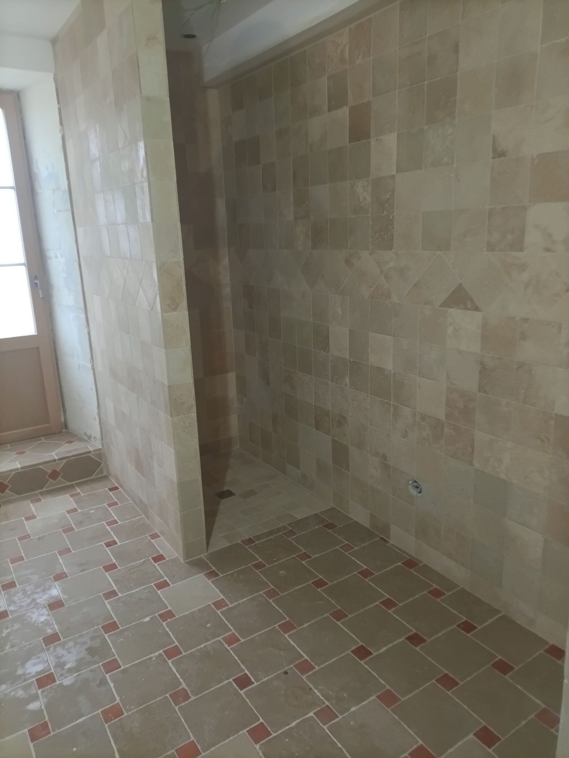 Salle de bains avec murs et sols carrelés beiges, comprenant une douche à l'italienne.