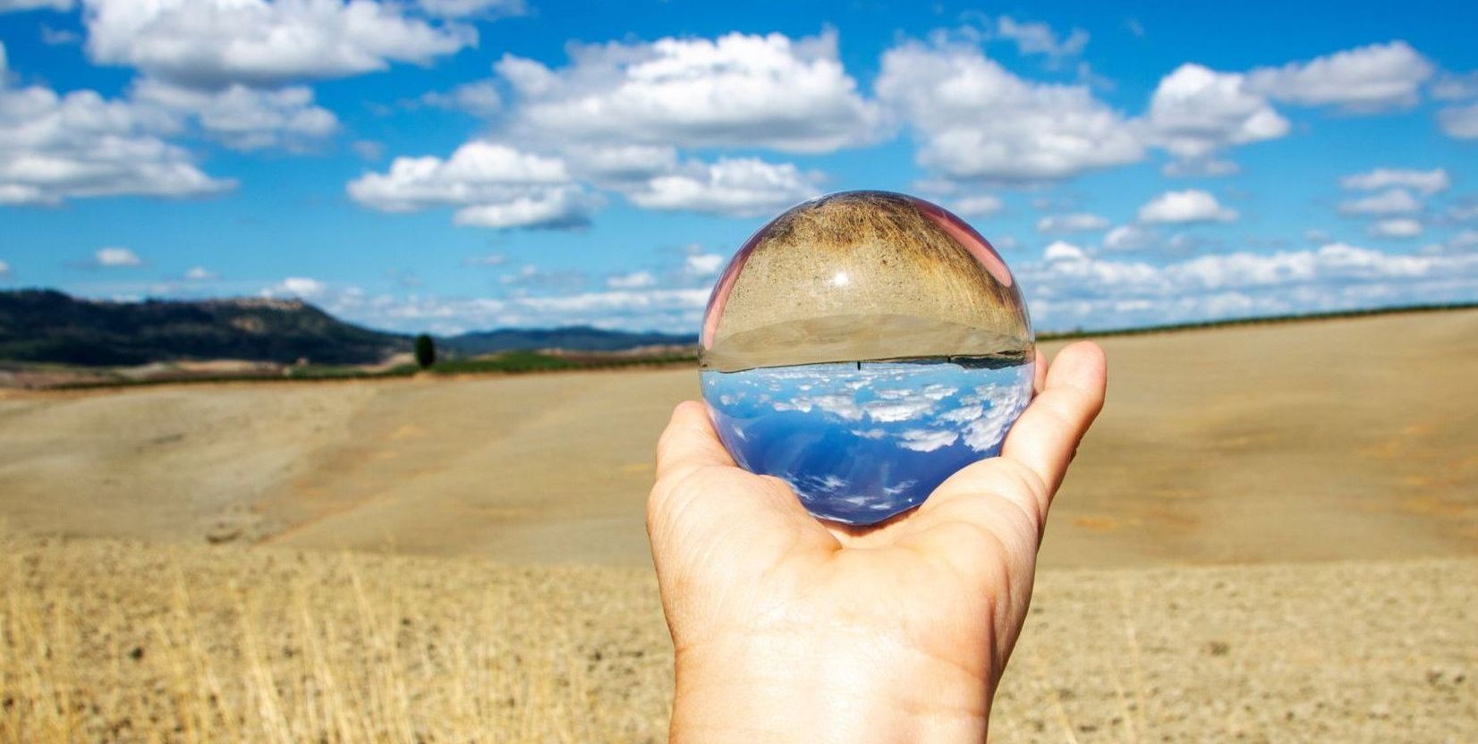 Une personne tient une boule de verre dans sa main au-dessus d'une route.