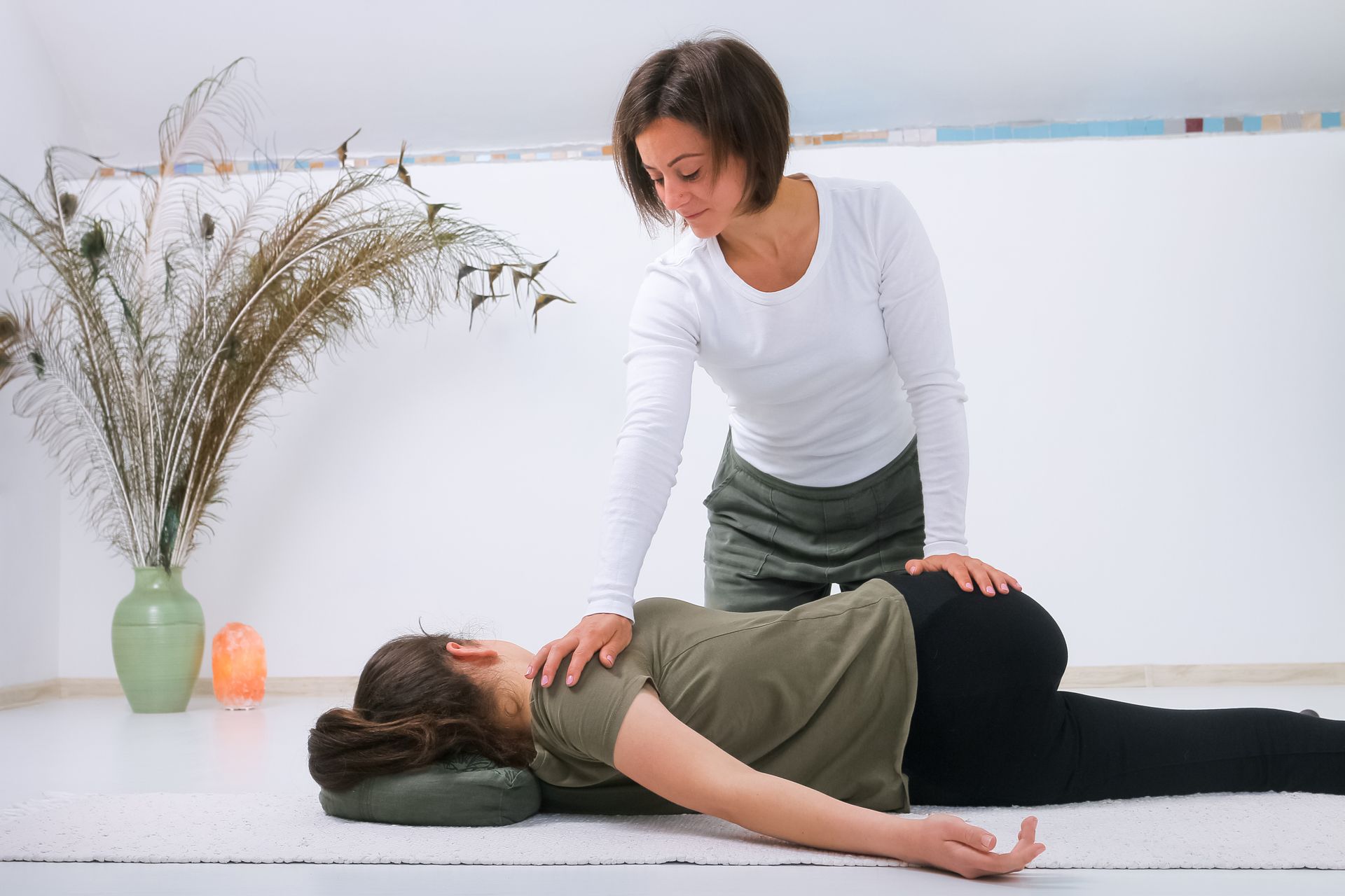 Une femme donne un massage à une femme allongée sur le sol.