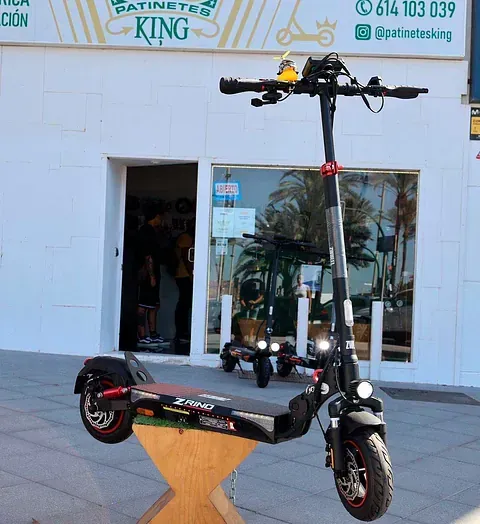 Un scooter está estacionado frente a una tienda llamada patinetes king