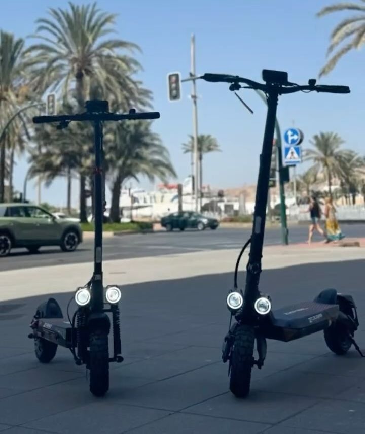 Dos scooters están estacionados uno al lado del otro en la acera.
