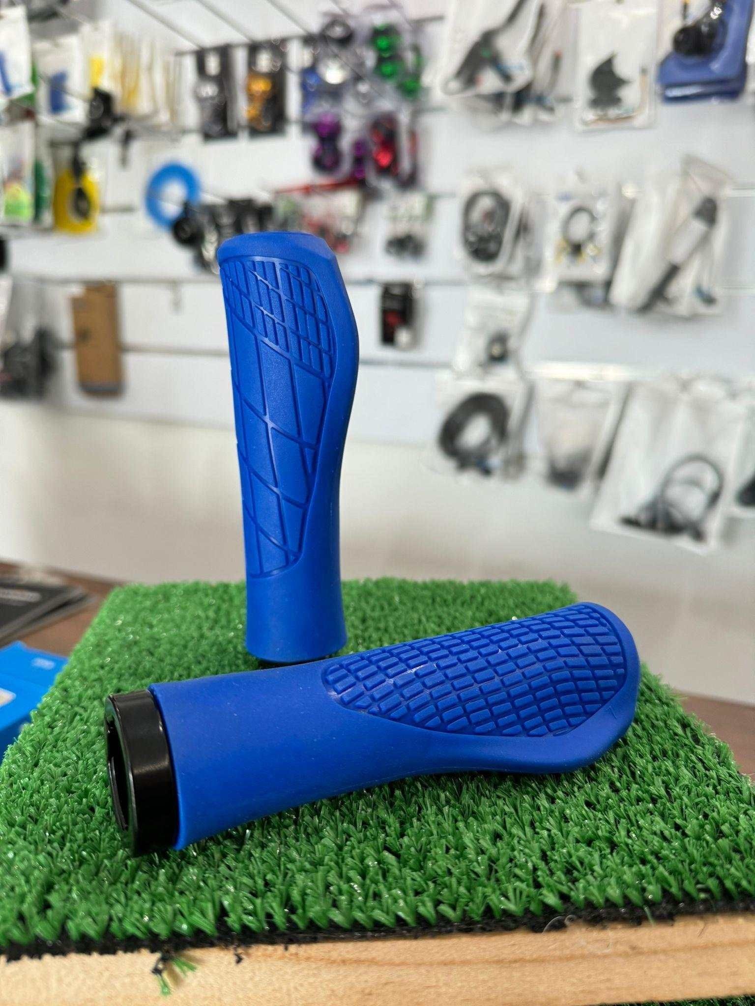 Un par de puños de manillar de bicicleta de color azul están colocados encima de un trozo de hierba.