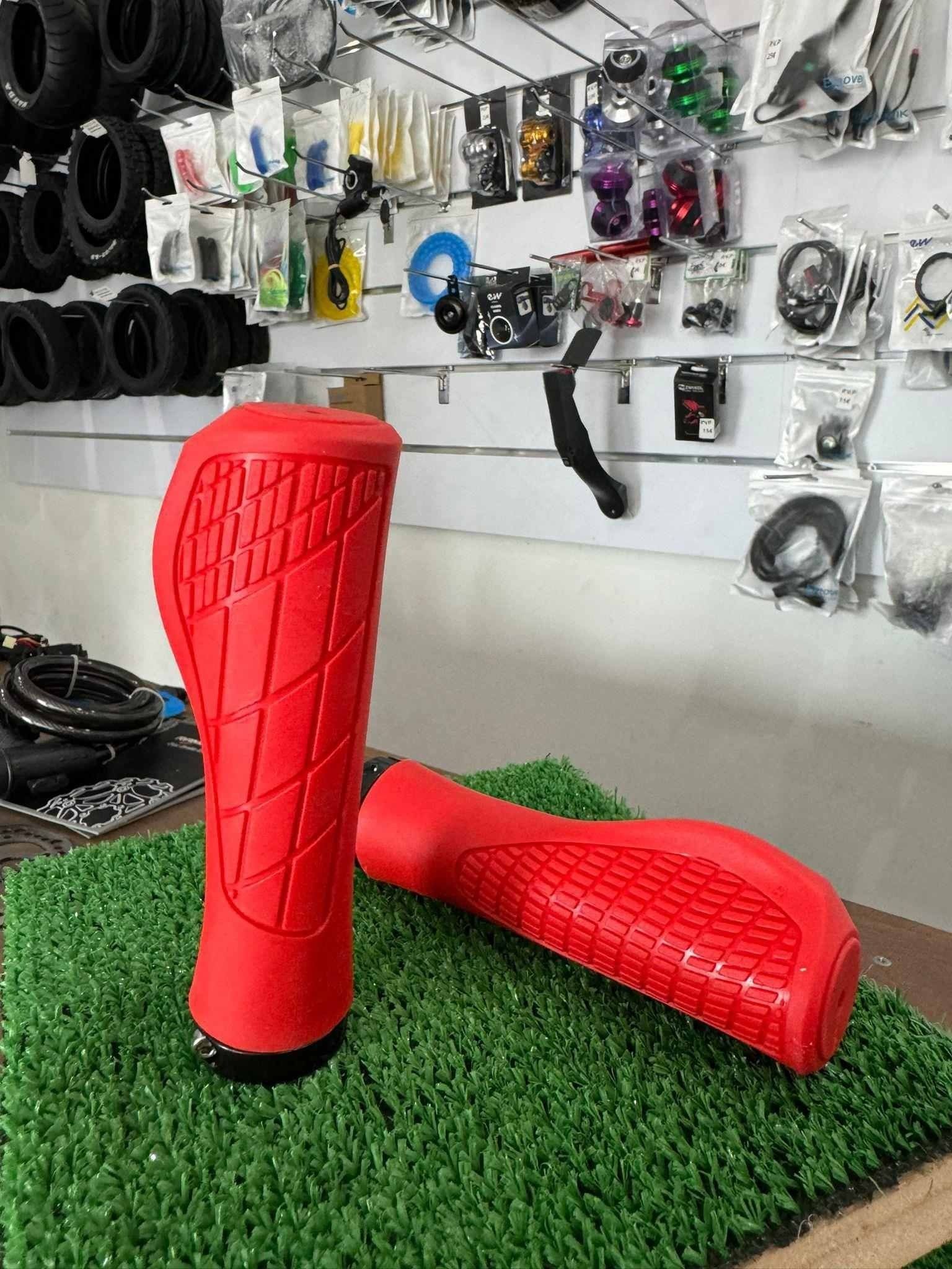 Un par de puños de manillar de bicicleta de color rojo están colocados encima de una mesa.