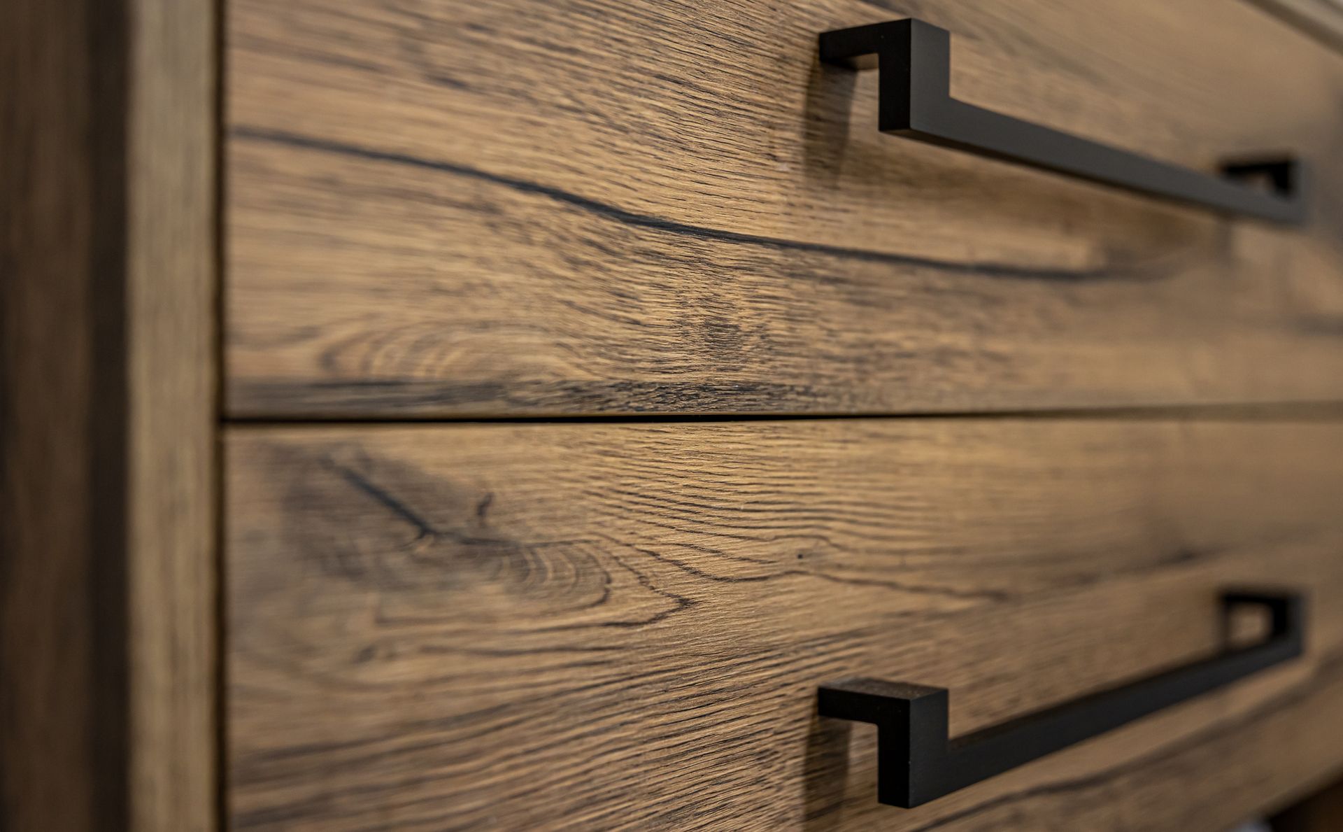 Gros plan de tiroirs de commode en bois avec poignées carrées noires.