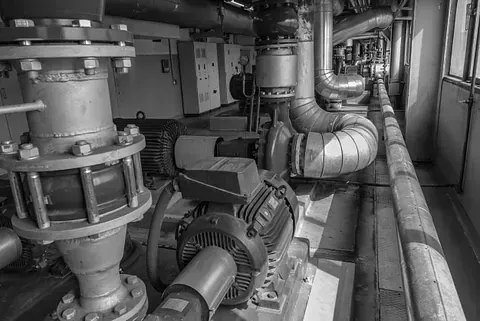 Una fotografía en blanco y negro de una fábrica con muchos tubos y motores.