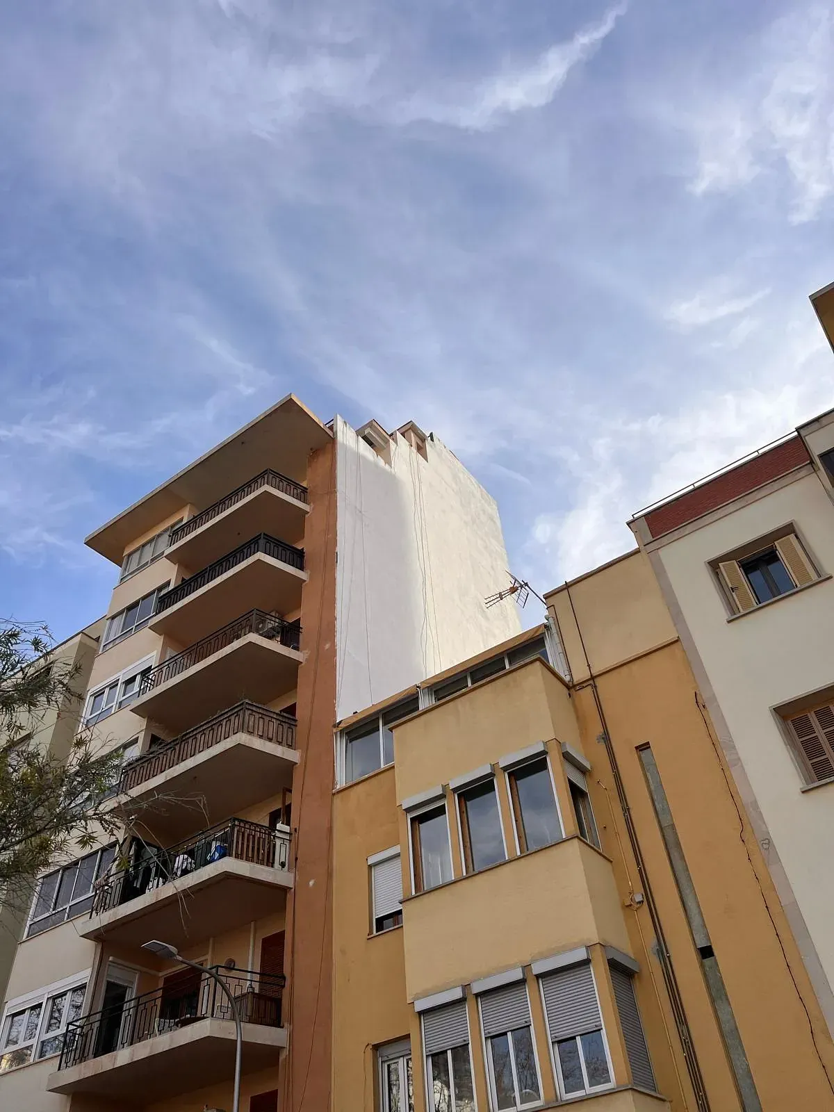 Un edificio con muchas ventanas y balcones está rodeado de otros edificios.
