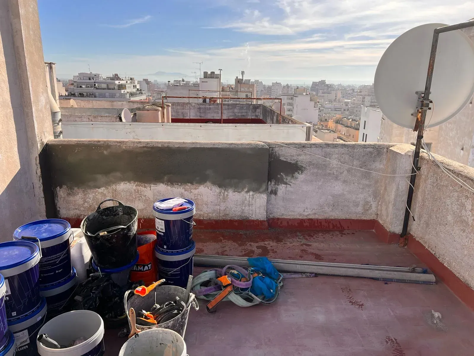 Un tejado con cubos de pintura y una antena parabólica.