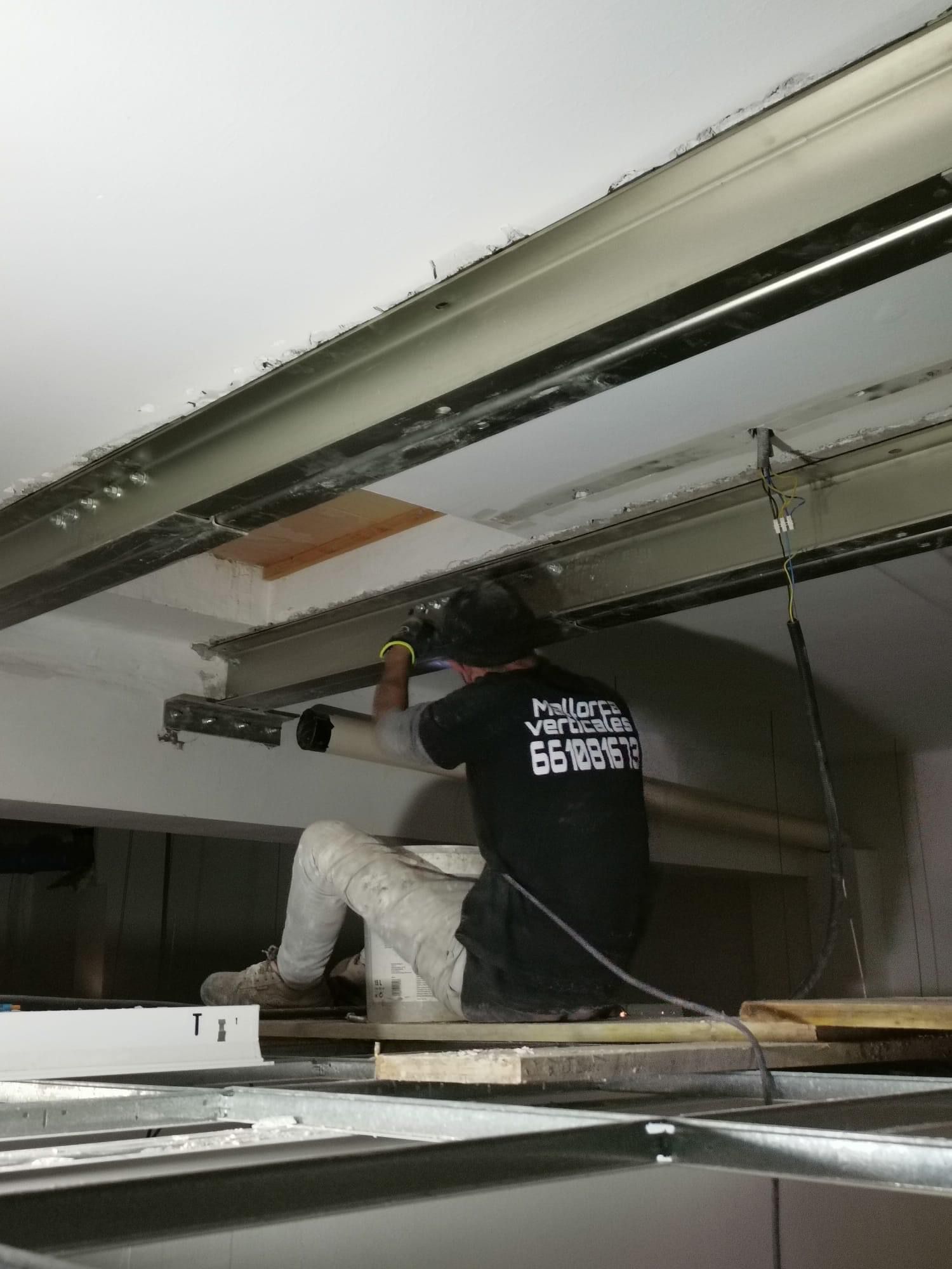 Un hombre con una camisa negra está trabajando en una puerta de garaje.