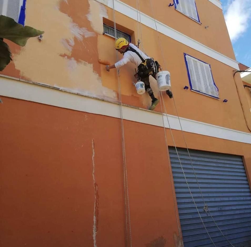 Un hombre está pintando el costado de un edificio.