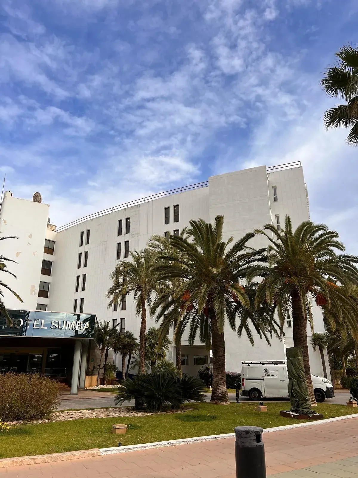 Un gran edificio blanco con palmeras delante.