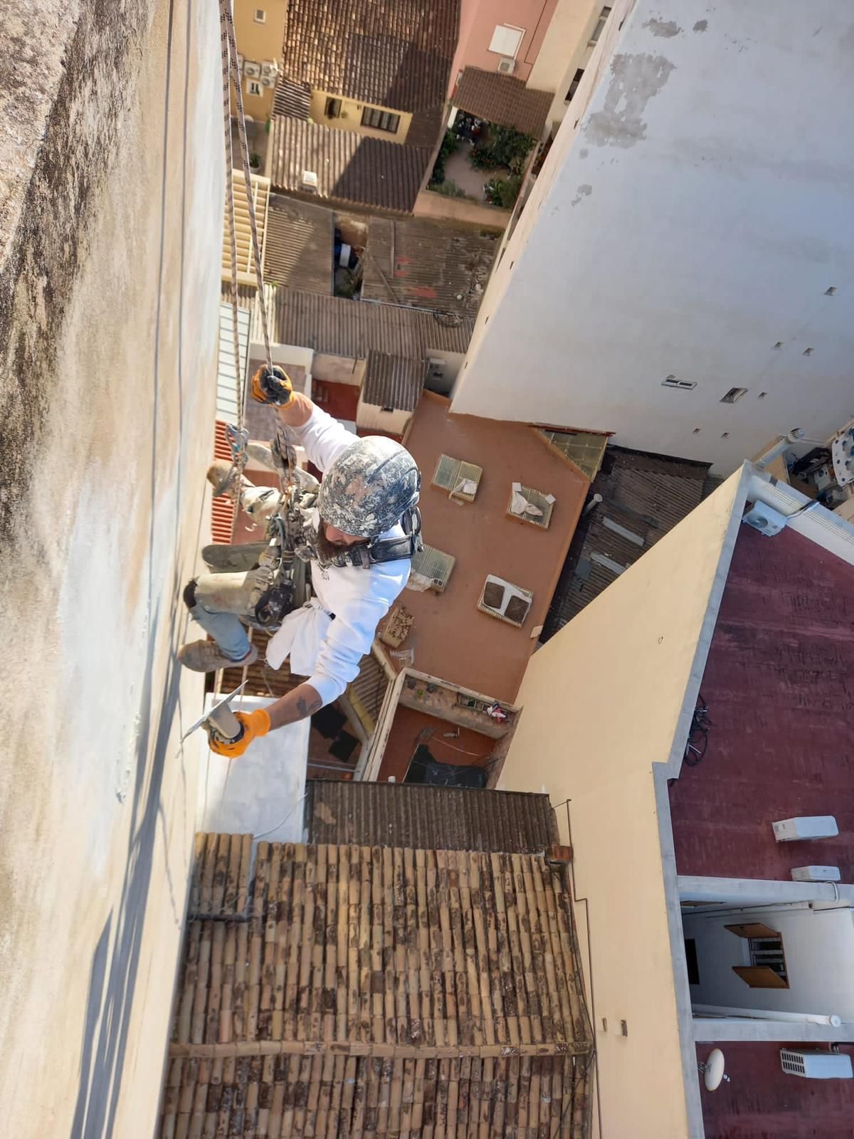 Un hombre está pintando el costado de un edificio.
