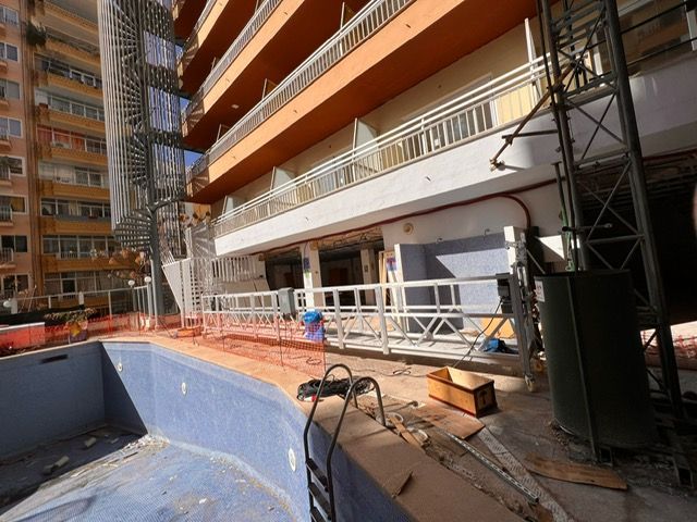 Un edificio en construcción con una piscina enfrente.