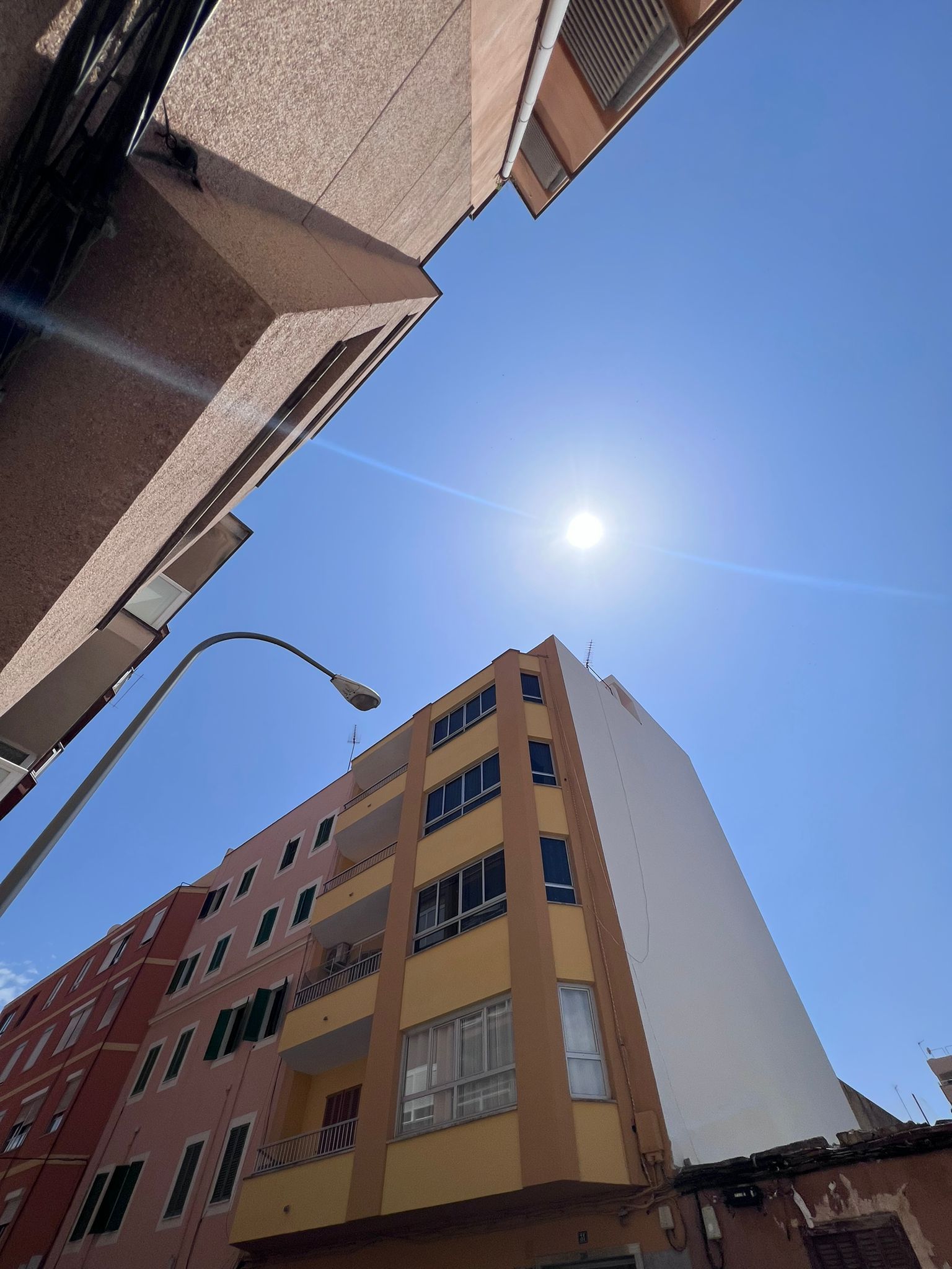 Mirando hacia arriba a un edificio con el sol brillando a través de las ventanas