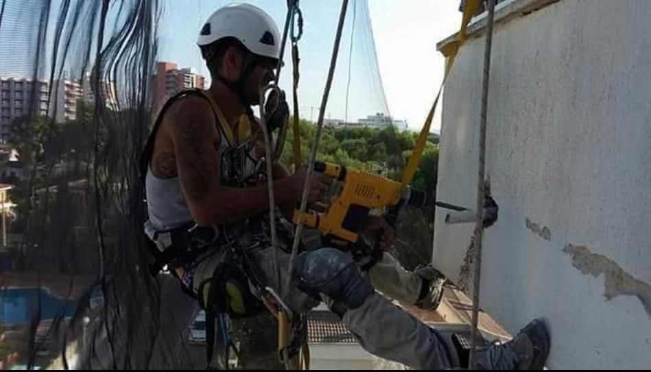Un hombre con casco está usando un taladro en un edificio.