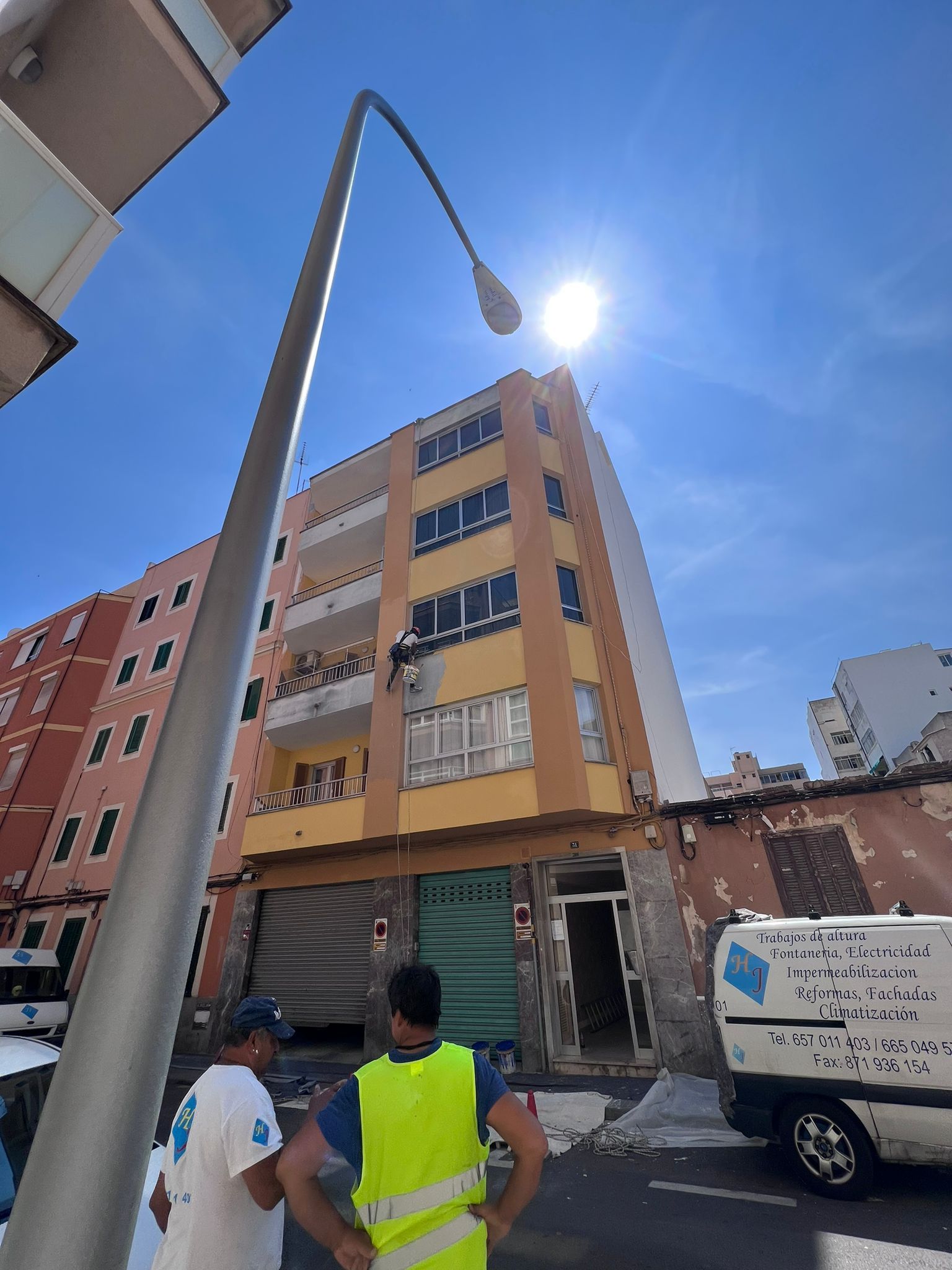 Un hombre con un chaleco amarillo está parado frente a un edificio.
