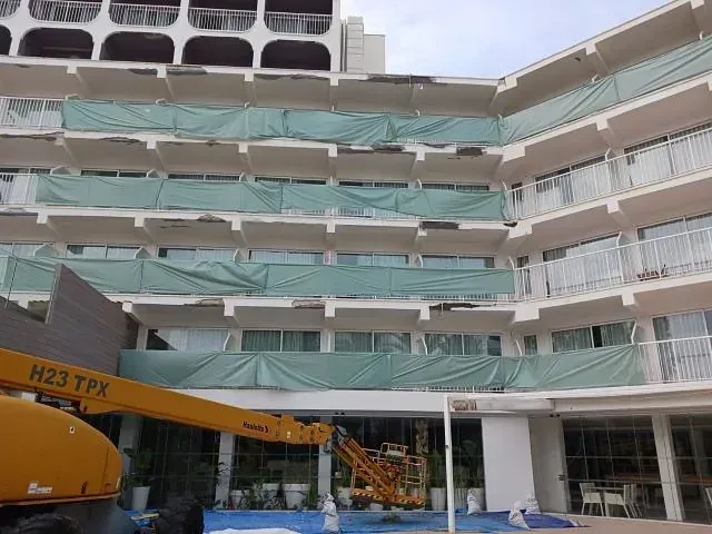 Un gran edificio con una grúa amarilla delante.