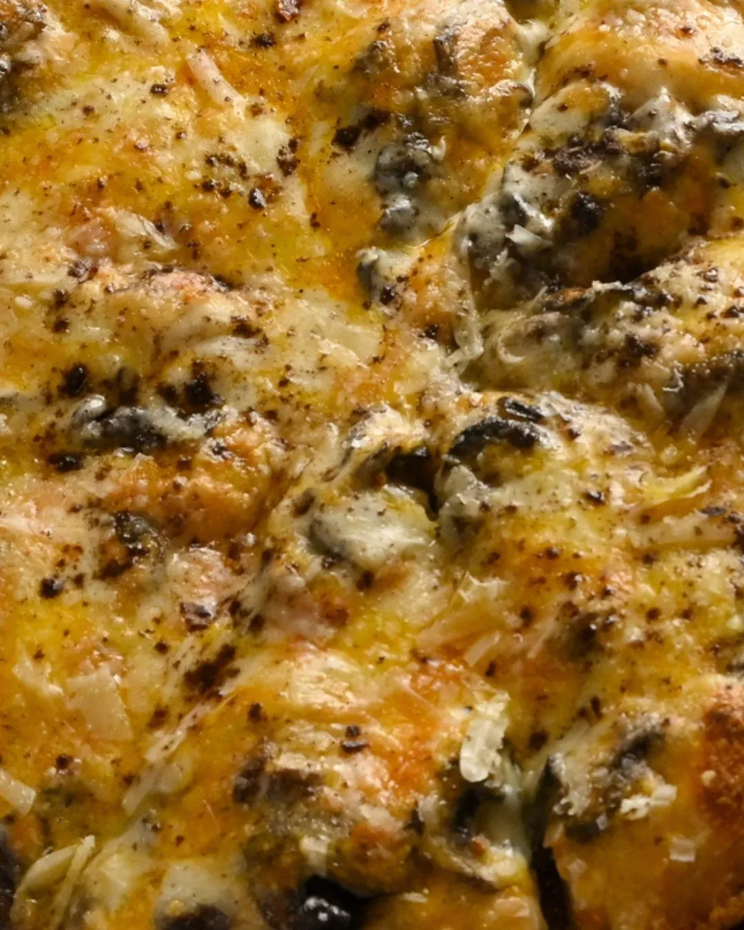 Primer plano de una pizza con queso y champiñones, mozzarella derretida y especias.