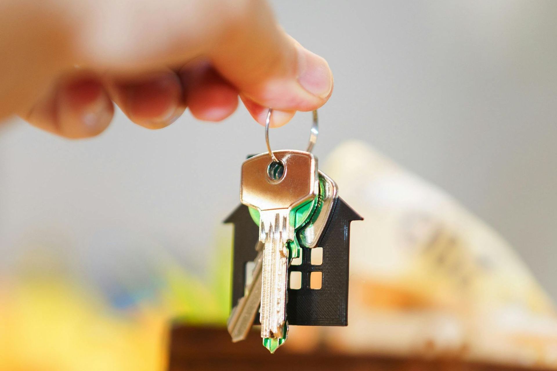 Una persona sostiene un par de llaves en un llavero con forma de casa.