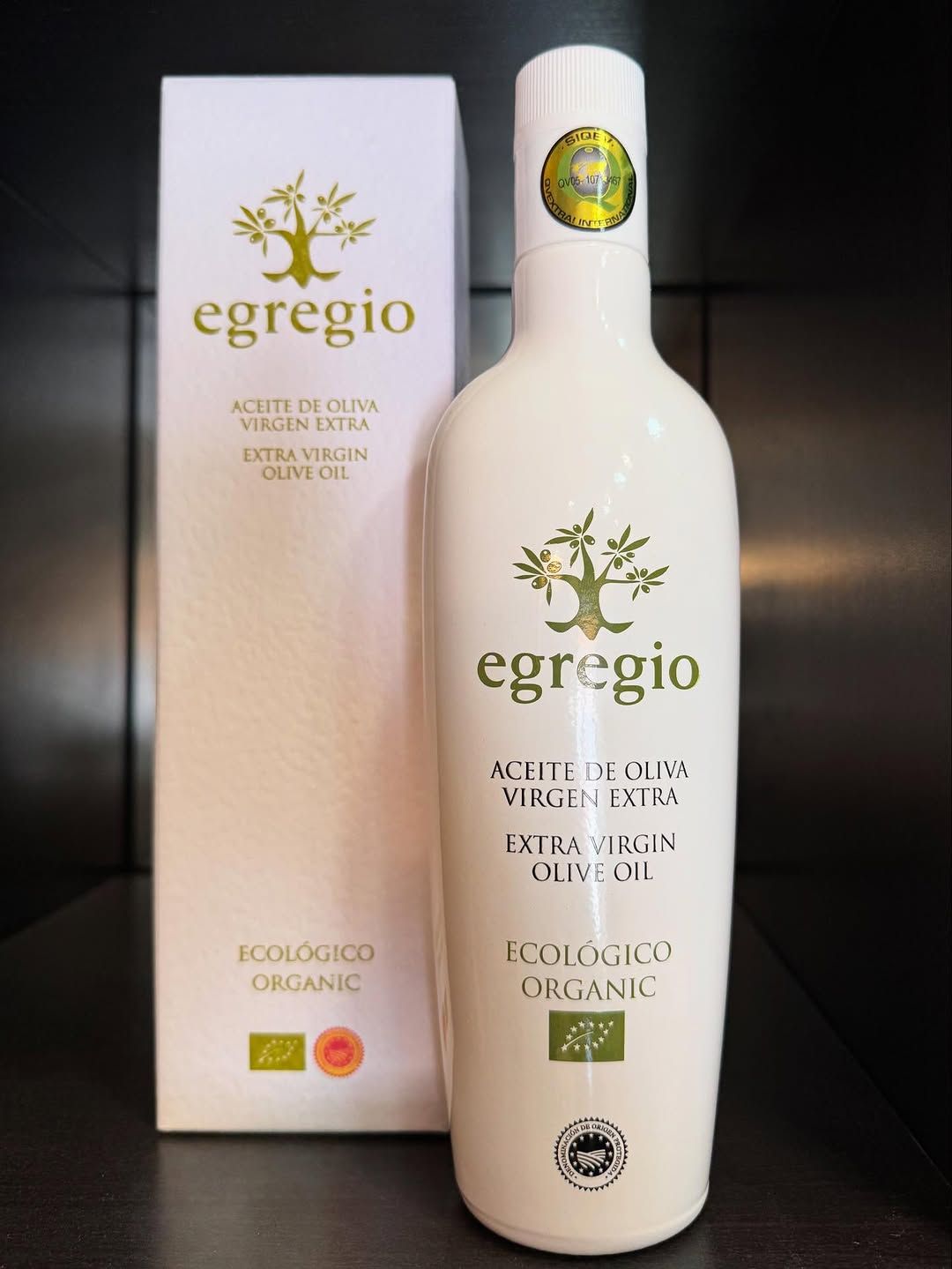 Botella y caja de color blanco de aceite de oliva virgen extra ecológico “egregio”, con texto en verde y logo del olivo.