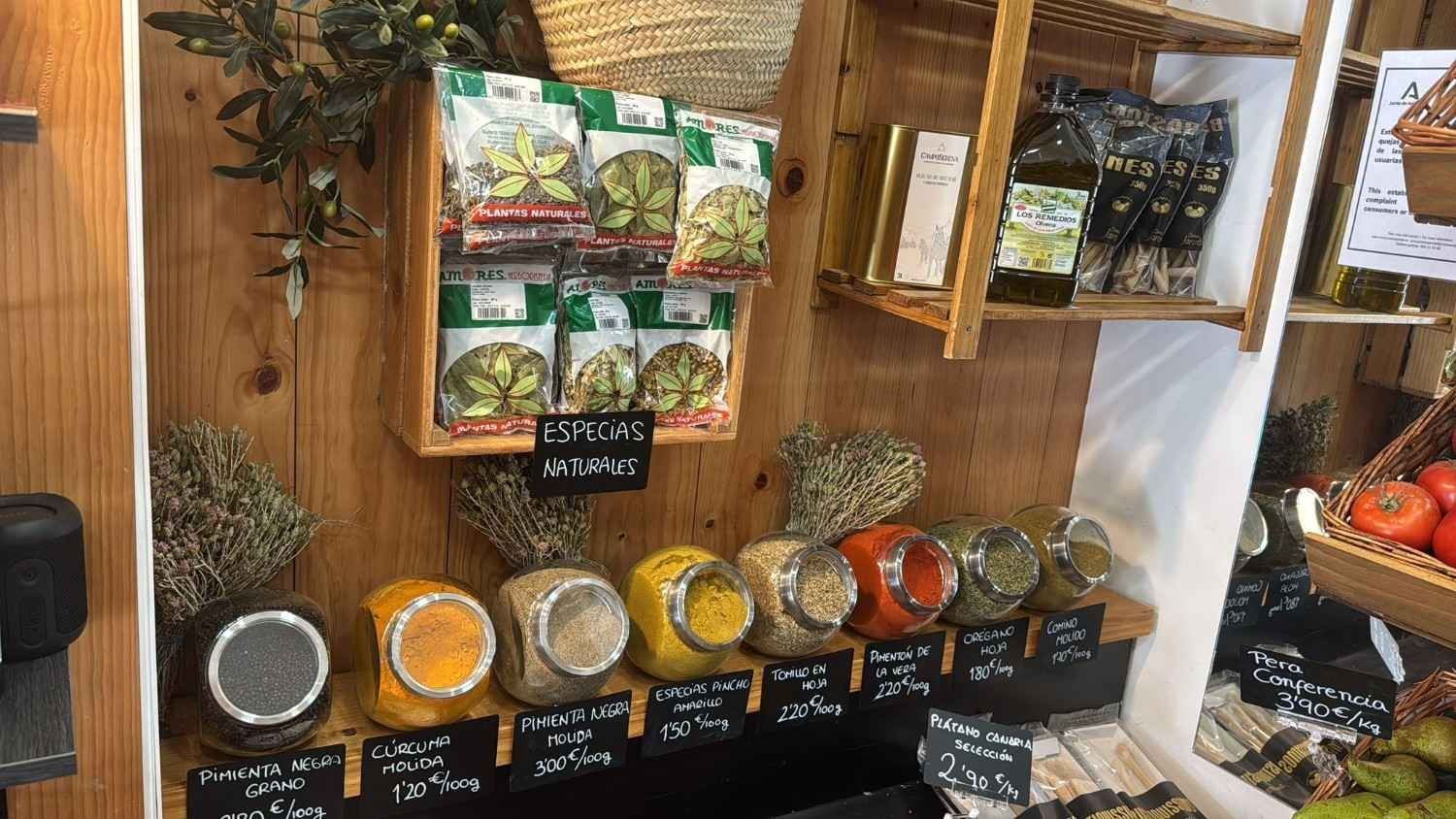 Una exhibición de hierbas, especias y aceite de oliva a la venta en una tienda con estantes de madera.