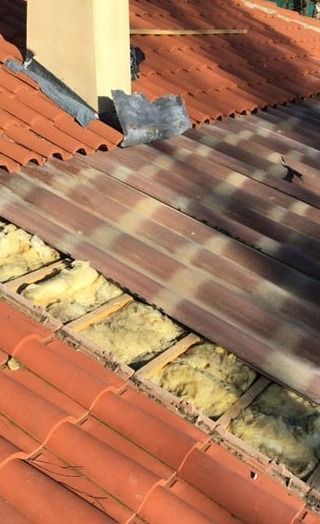 Un gros plan d'un toit avec une cheminée en arrière-plan.