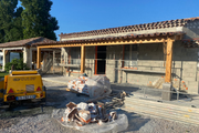 Une remorque jaune est garée devant une maison en construction.