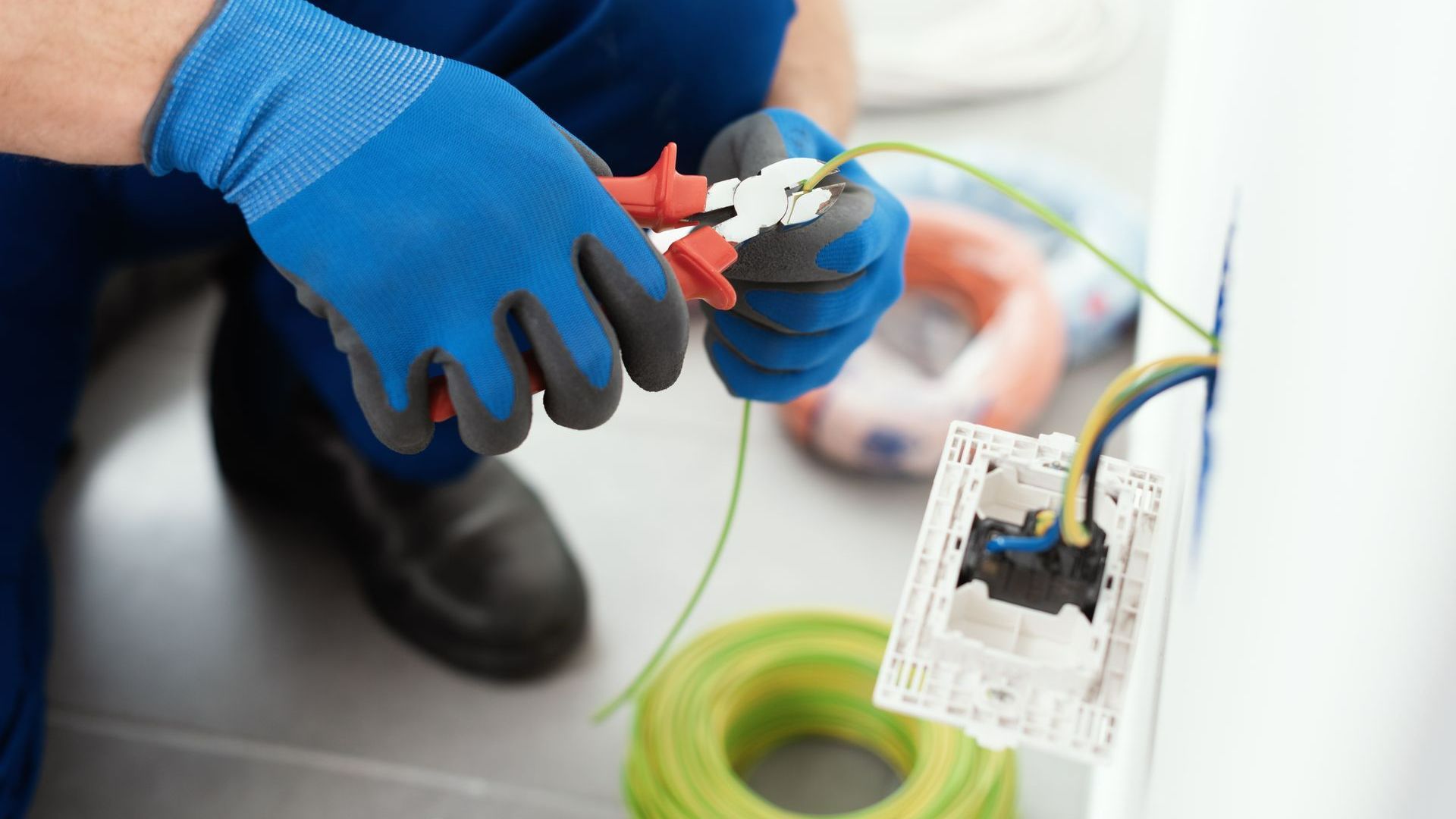 Gros plan sur les mains d'un électricien qui branche une prise électrique