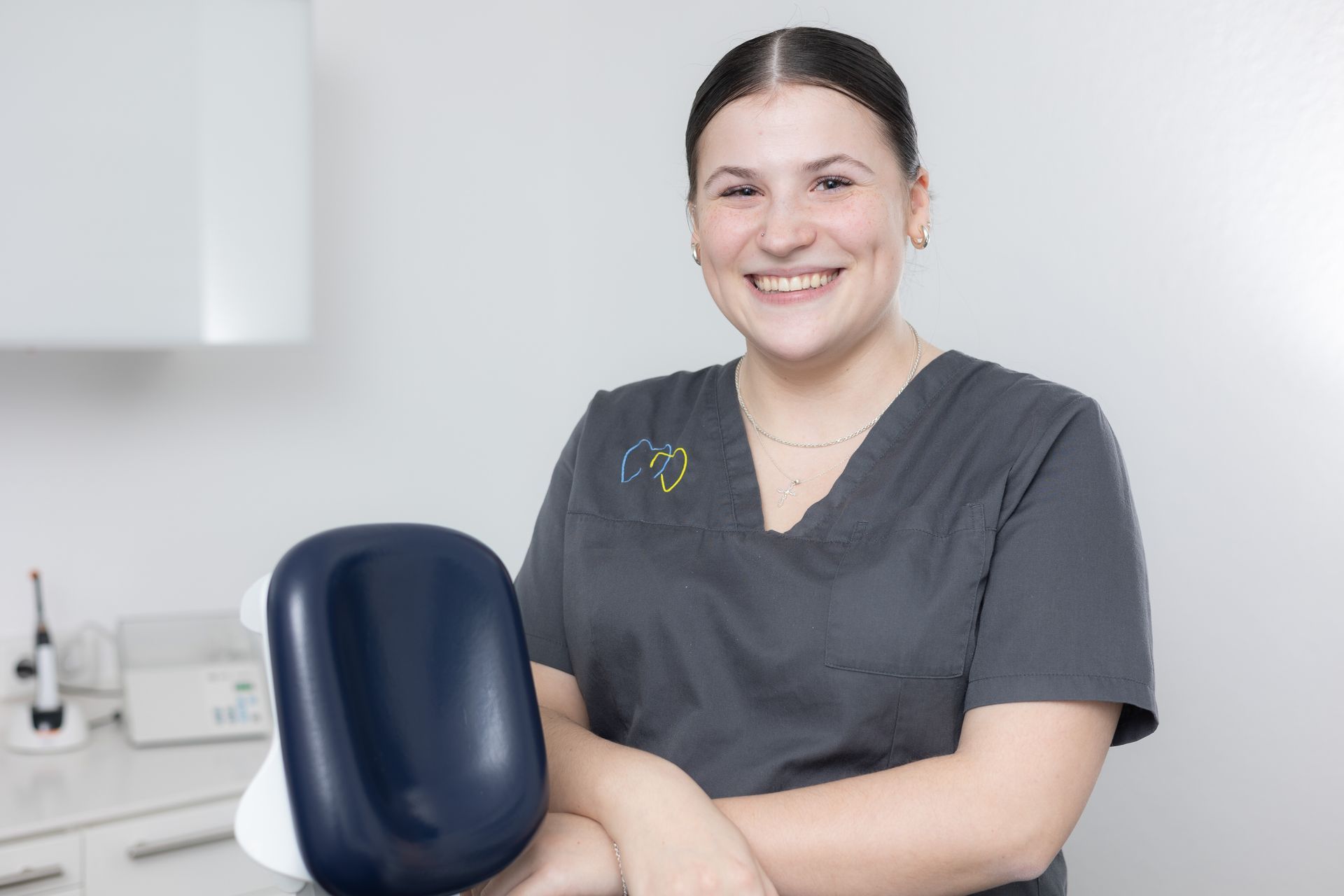 Lächelnde Frau im OP-Kittel in einer Zahnarztpraxis.